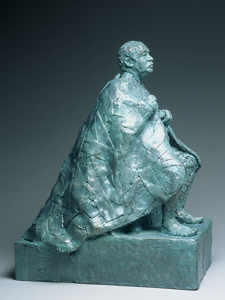 Seated male figure with patchwork cape side view in fiberglass cast by William Casper.