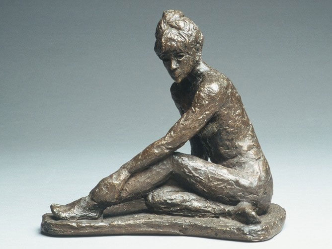 Female seated with one leg outstretched and one leg folded in cast plaster by William Casper.